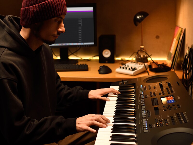Osoba grająca na instrumencie klawiszowym PSR-SX620 w domowym studiu.
