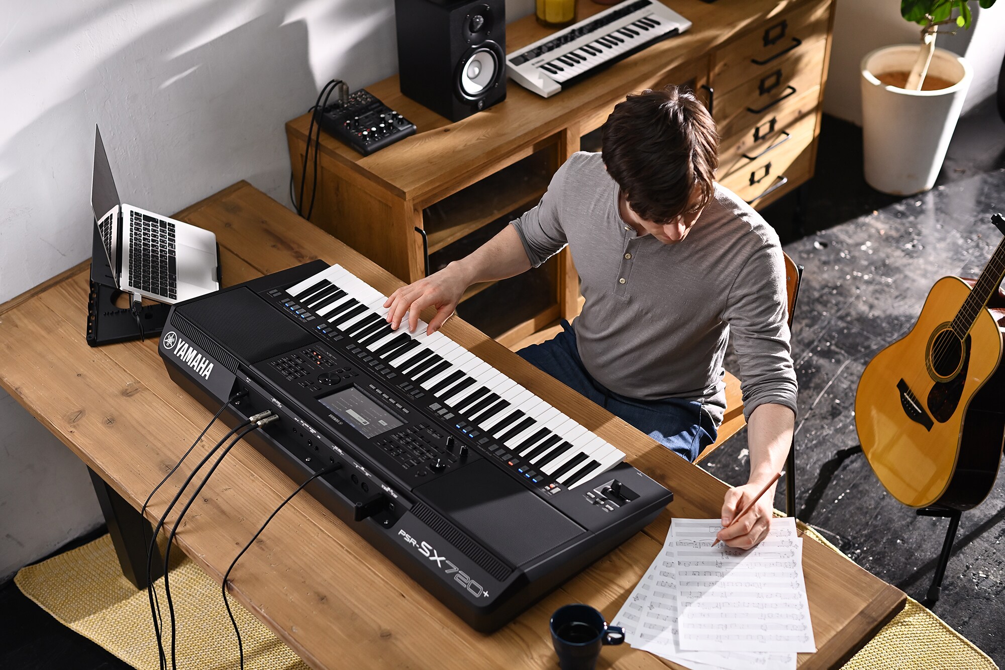 Zdjęcie osoby piszącej na nutach podczas gry na aranżerze Yamaha Arranger Workstation PSR-SX720+