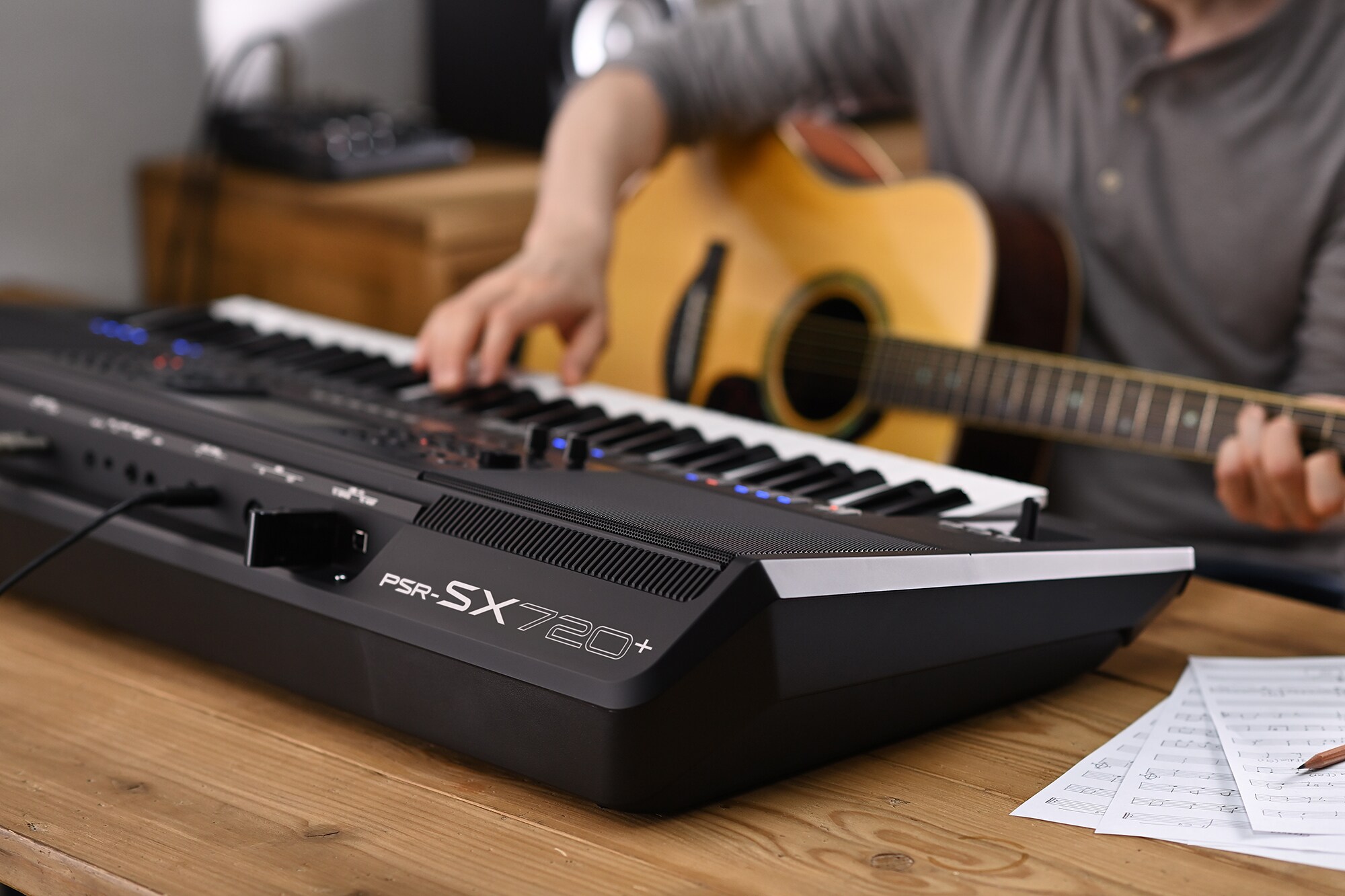 Zdjęcie osoby grającej na aranżerze Yamaha Arranger Workstation PSR-SX720+ z gitarą